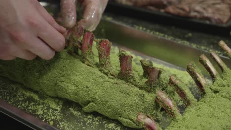 Chef-prepares-venison-meat-ribs-on-metal-tray-before-baking