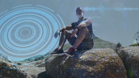 Animation-of-round-scanner-and-data-processing-over-african-american-senior-man-sitting-on-the-rocks