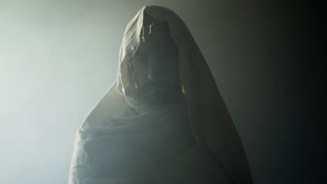 jesus christ in glowing light, resurrected on easter sunday inside empty tomb in bright, shining light, wearing white hood and robe. cinematic christian visual.