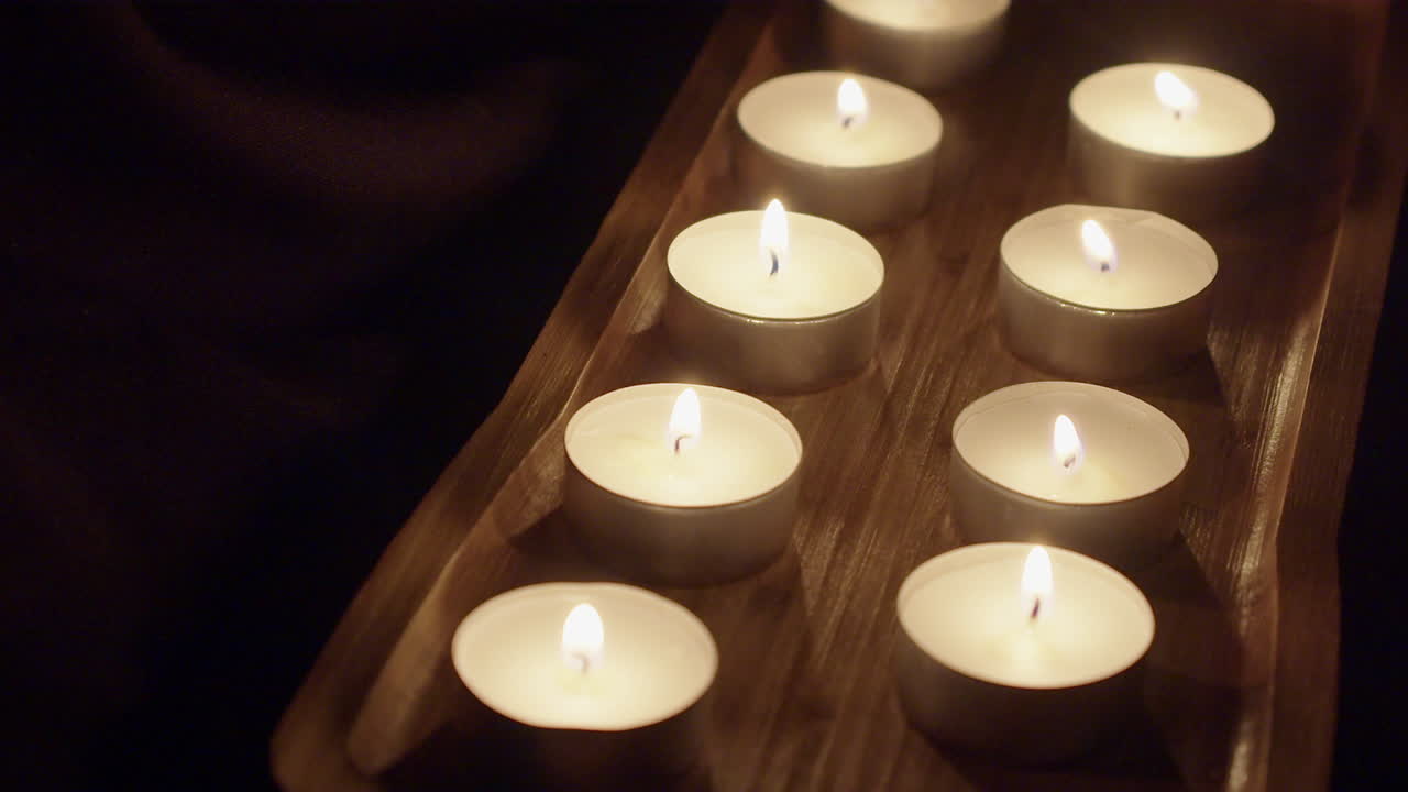 Lumini da tè bruciano piccole fiamme in un vassoio decorativo in legno, con spazio per il testo