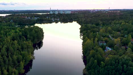 calm lake filmed from above with block buildings in distance.