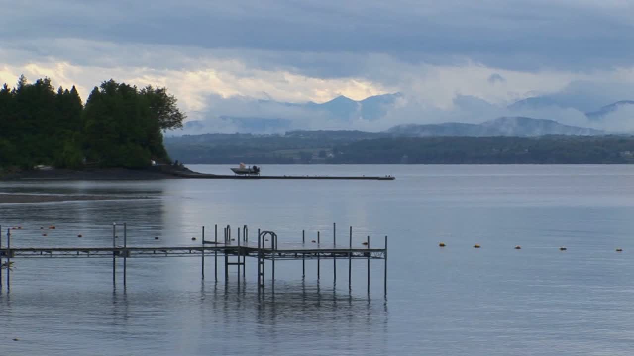 작은 부두는 버몬트 주 챔플레인 호수의 회색과 흐린 하늘 아래 잔잔한 바다로 확장됩니다.