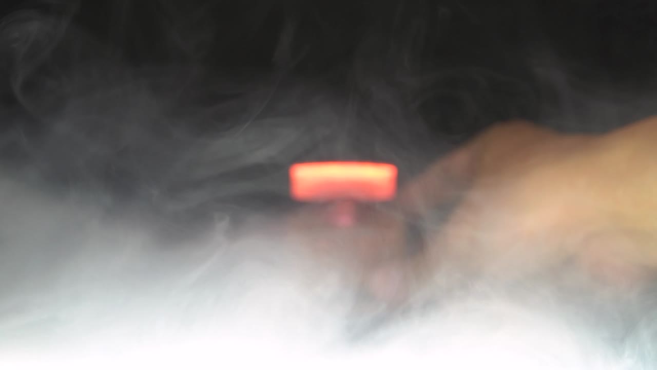 бутылка парфюмерии с оранжевой жидкостью. эффект дыма. черный фон