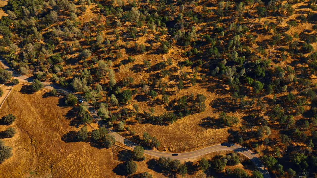 Panorama of the rocky landscape covered with trees. Car goes by the highway in Sierra National Forest, California, USA. Aerial view.