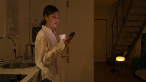 woman using phone in kitchen at night