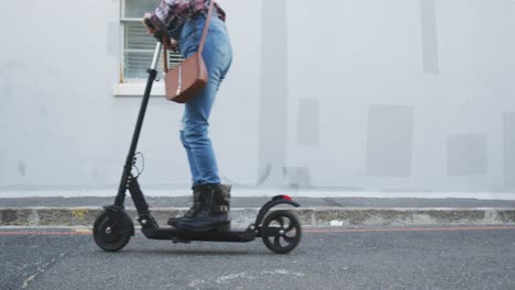 mujer de raza mixta usando scooter eléctrico