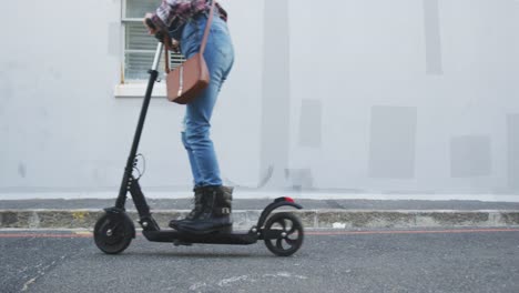 mixed race woman using electric scooter