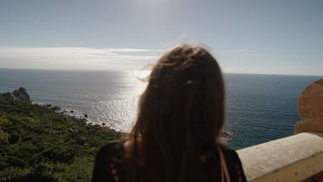 a traveler gazes out over tangier’s coastline, with the sea shimmering under sunlight