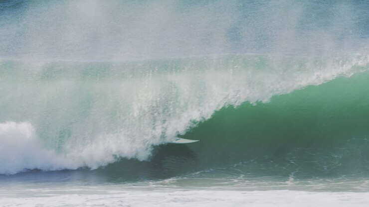Surfer riding a powerful wave in slow motion during golden hour, with dramatic lighting and crashing water spray