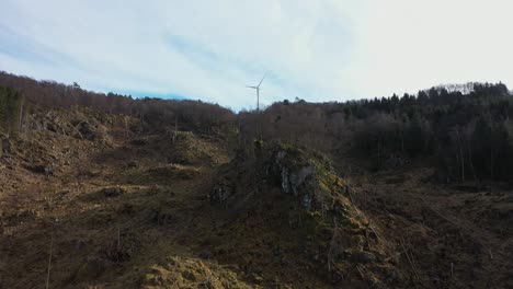 flying up hillside against rotating wind turbine in midtfjellet wind park - one single turbine producing electricity along coast of norway