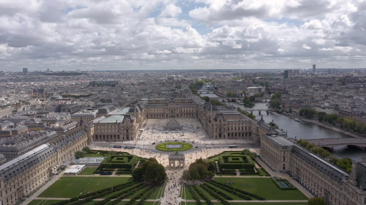 Aerial drone view flying sideways across the Louvre, Tuileries Garden, Seine River and Place du Carrousel surrounded by the historic Parisian skyline