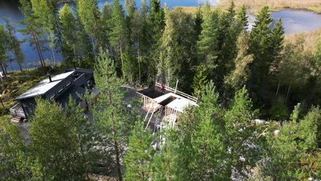 pequeño edificio en construcción en un paisaje forestal cerca de un lago, vista aérea