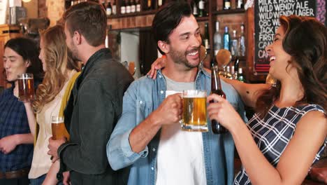 Smiling-group-of-friends-interacting-while-having-bottle-of-beer