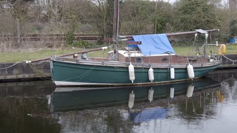 old wooden sailboat moored on narrow rural countryside canal marina