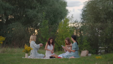 young women conduct clay modeling classes in the open air. one girl takes notes on her smartphone conducts correspondence online. communication hobbies women's circle creative activity.