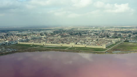 Medium-altitude-aerial-view-of-Aigues-Mortes,-pink-salin-in-foreground.-France