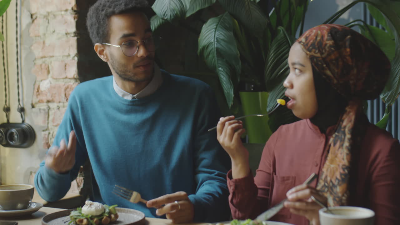 Muslim Couple Eating Lunch and Talking in Cafe