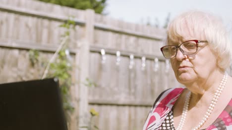 close up on elderly woman as she types on a laptop, acting confused figuring out what to type