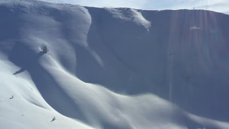 aerial view flying up a snow covered mountain slope to reveal a mountain skyline beyond the ridge