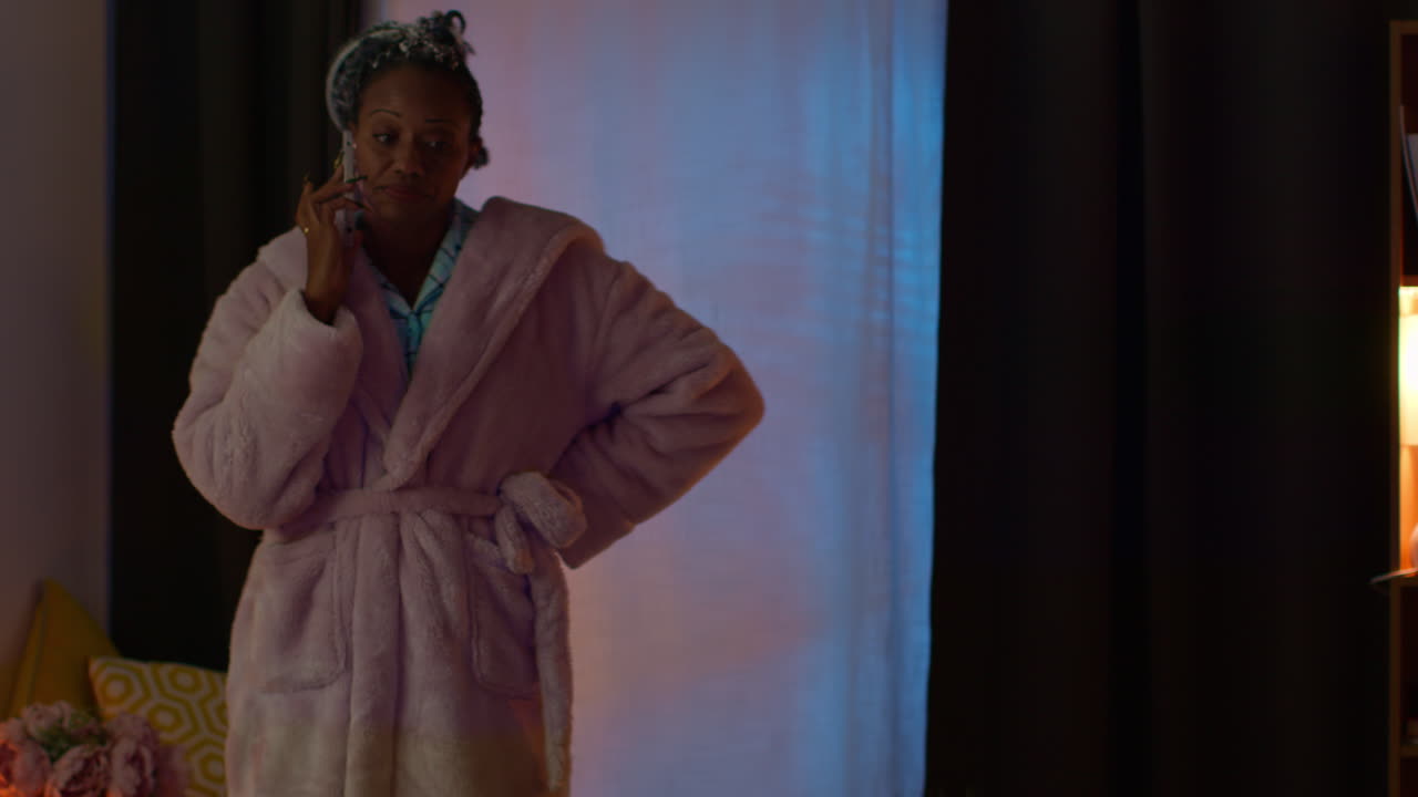 Woman talking on phone in robe at night
