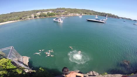 man jumping from a cliff with boats in front. australia