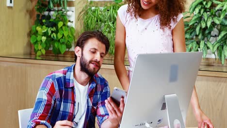 Executive-showing-his-mobile-phone-to-colleague-in-office