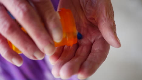 an elderly woman pouring pills from a prescription medicine bottle into her wrinkled, aged hand to cure her illness