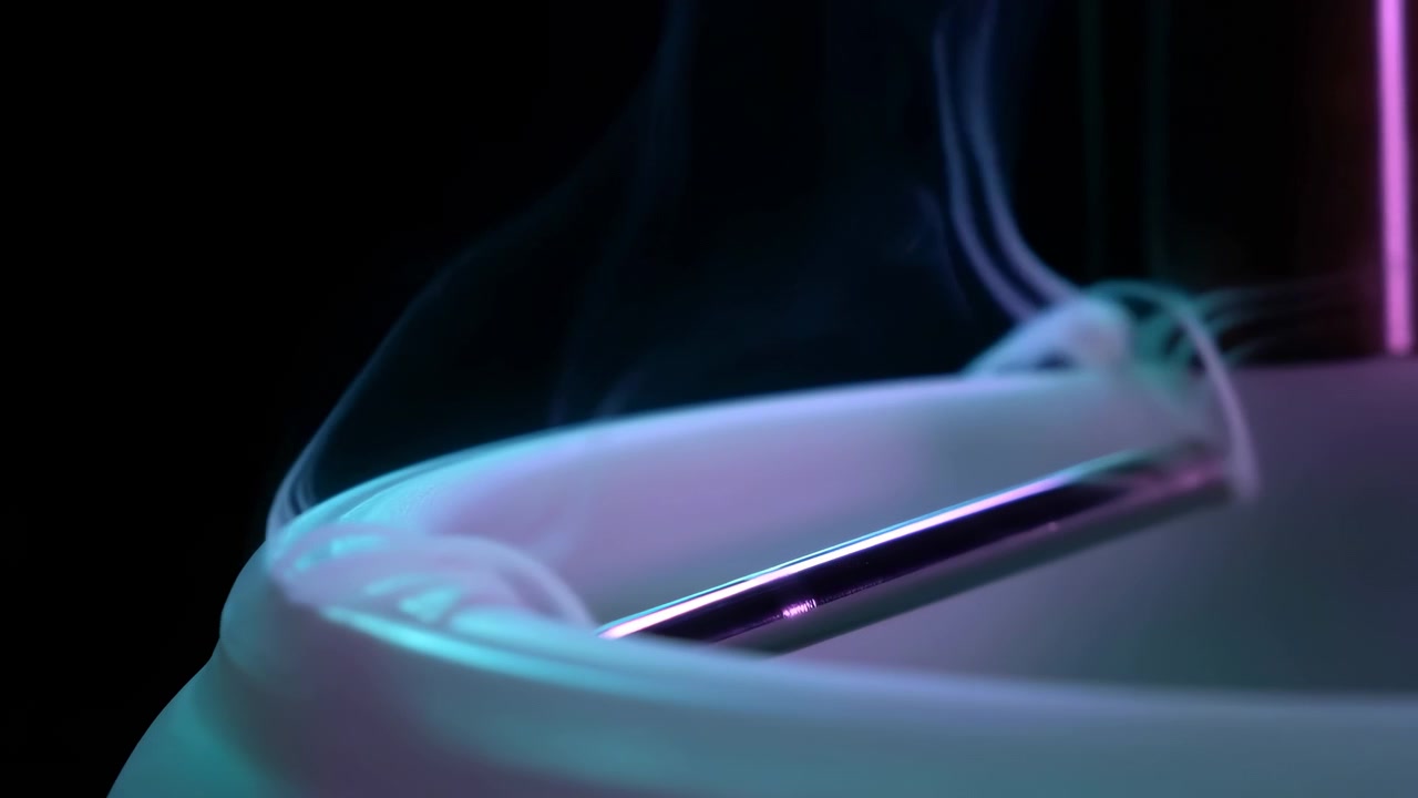 Extreme close-up of polished chrome faucet spout set into glossy ceramic sink rim, with thin vapor curling upward, wet reflections, cyan and magenta glow, and dark modern spa atmosphere