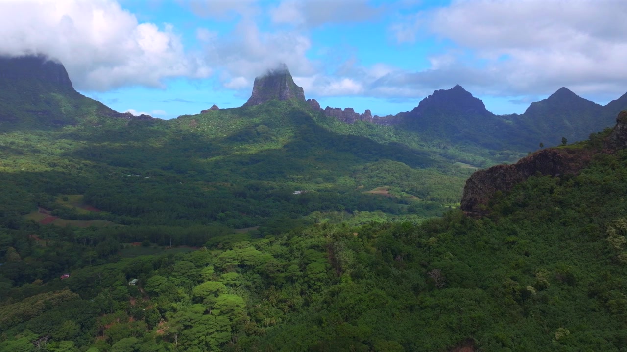 Dramatiska vulkaniska taggiga toppar, oländig terräng, Mount Rotui, Mt Toheia, Moorea, Franska Polynesien, flygdrönare, Belvedere Lookout, landskap, Cooks Opunohu Bay, solig morgon, blå himmel, låga moln, cirkel vänster.