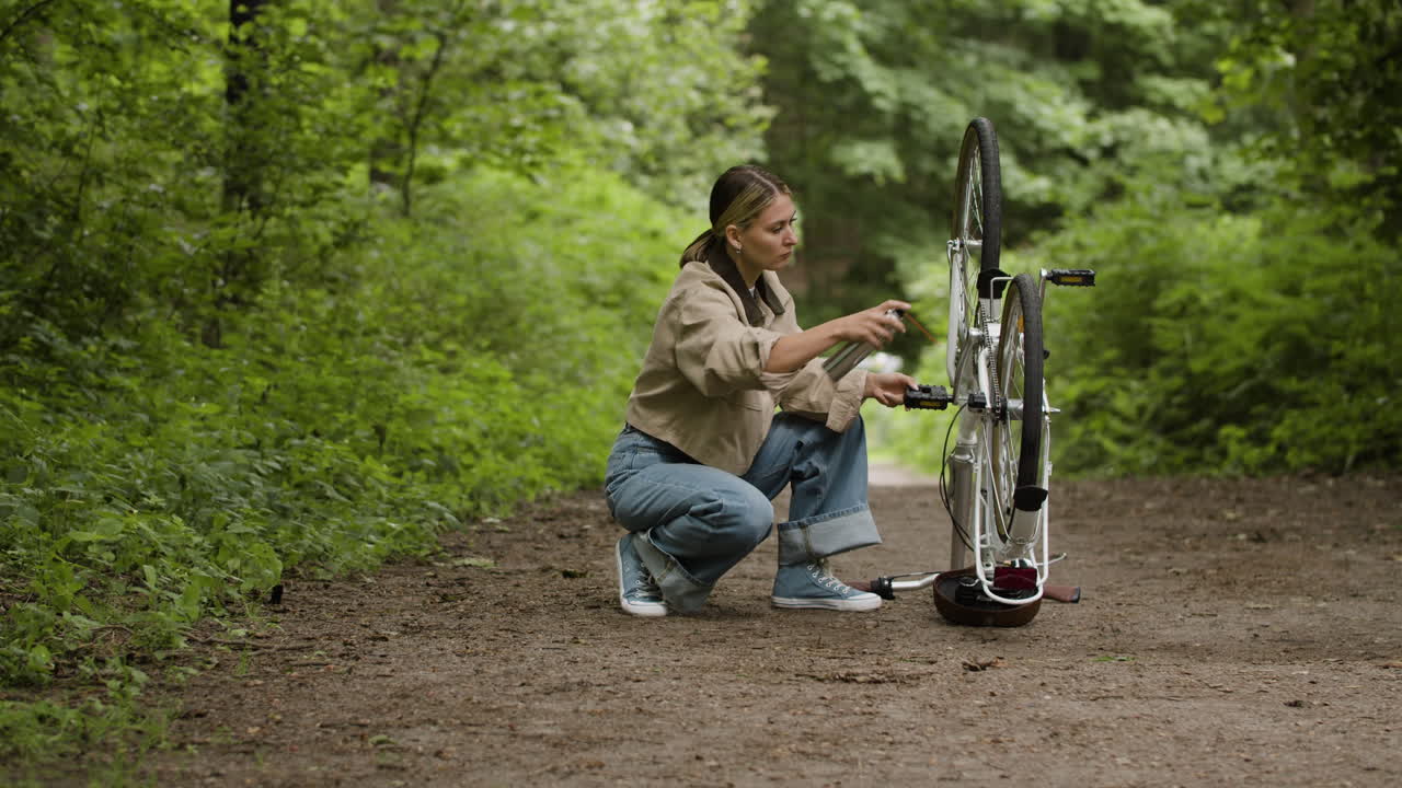 Woman repairing her bicycle in the forest