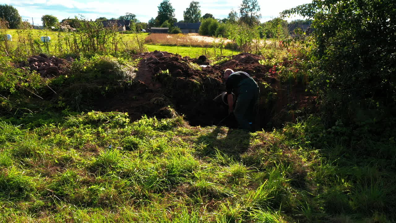 Elderly man digging ground with shovel on sunny day, dolly forward view