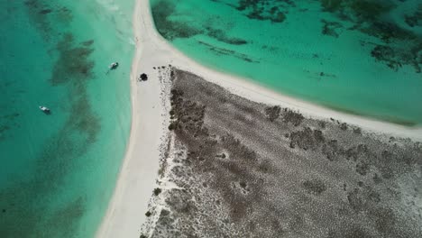 una estrecha playa de arena y agua turquesa que se encuentra con un escarpado paisaje rocoso, vista aérea
