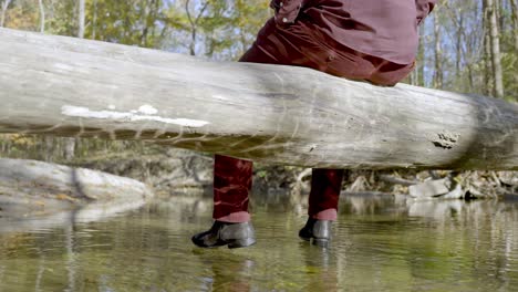 disparo por detrás de un hombre con ropa burdeos sentado en el baúl sobre el río, tiro de muñeca, concepto de soledad