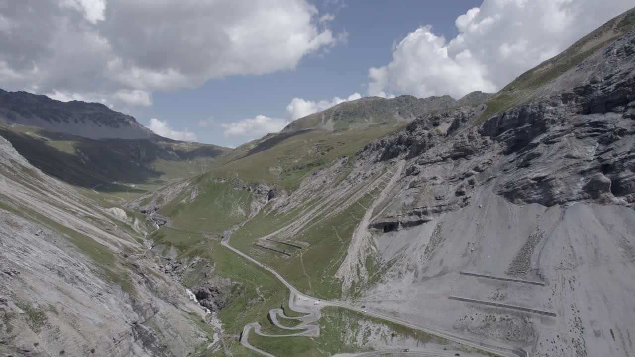 video with frontal plane drone advancing on ascent of the stelvio pass with horizon with snowy mountains
