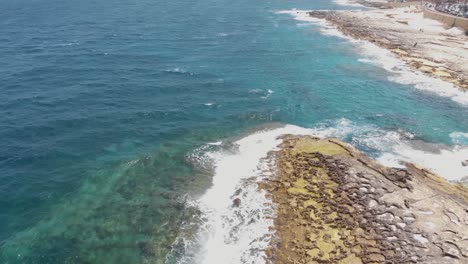 Paseo-Marítimo-Rocoso-Bañado-Por-El-Mar-Mediterráneo-En-La-Ciudad-De-Sliema,-Malta---Tiro-De-Revelación-De-Inclinación-Aérea