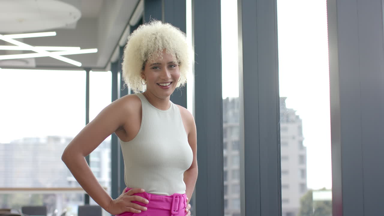 Smiling woman standing confidently in modern office near large windows, copy space