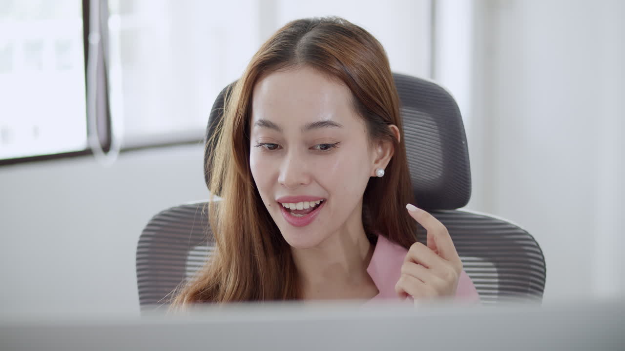 A woman joyfully participates in remote work showcasing her engagement and positivity in a bright office.