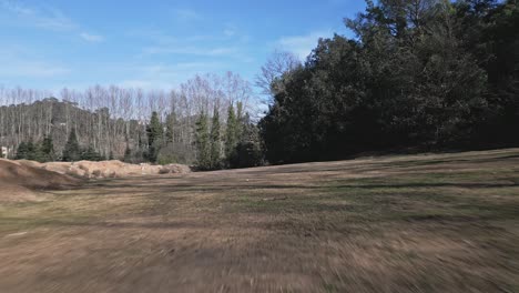 Aerial-Drone-Dolly-Out-Ground-Forest-Meadow-Landscape-in-Morning-European-Land,-Countryside-with-clear-Skyline,-Dry-earth-tones,-Dark-green-pine-trees