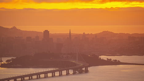 Time-lapse-Del-Puente-De-La-Bahía-Y-El-Horizonte-De-San-Francisco,-Puesta-De-Sol-Brumosa-En-EE.UU.