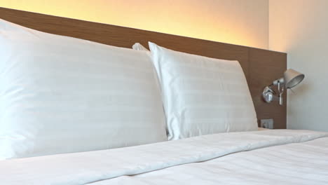 close-up pan across pillows arranged on a hotel bed