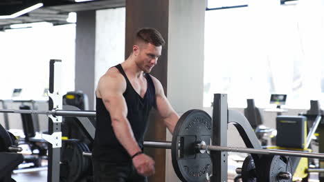 man training in the gym. muscular man putting heavy plates on barbell and lifting in gym
