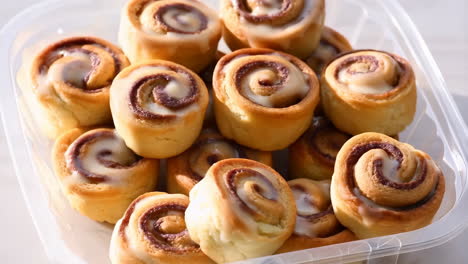 a container full of mini cinnamon rolls with icing