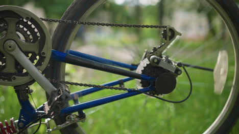 close-up of bicycle's rear wheel and gear system as the wheel rotates slowly, the chain and cogwheel are in focus, while the background is blurred, featuring a hint of someone walking