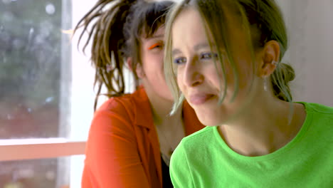 young woman with piercings talking while her friend is eating pizza and drinking beer