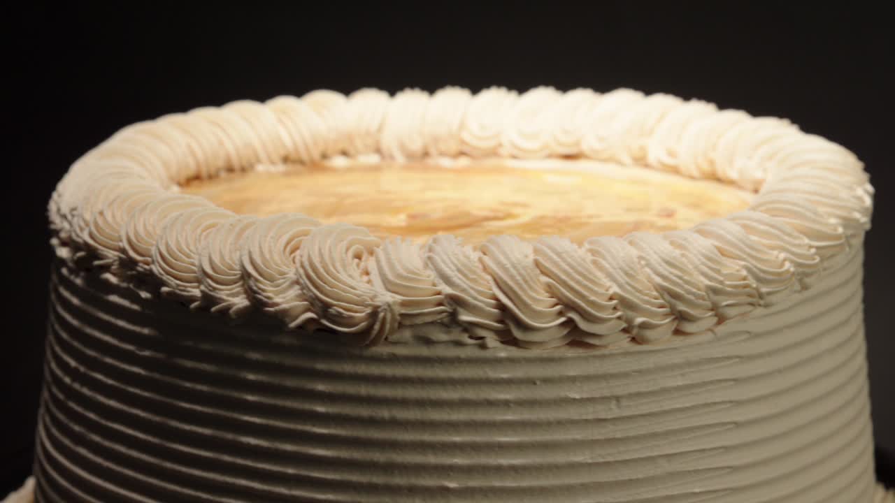 Nærbillede af Cajeta dulce de leche mælkekaramelkonfekt og sukkerkage i en roterende optagelse på sort baggrund. Velsmagende, lækkerbisken, pastel, mexicansk, argentinsk, latinamerikansk.