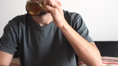 close up of a man sitting on the couch drinking hot tea