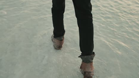 follow cam of man wearing jeans and leather boots walking in ankle deep water