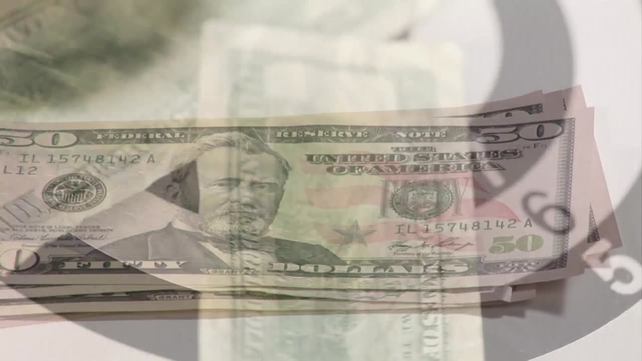 Animation of hand counting american dollar bills spinning over bull's eye