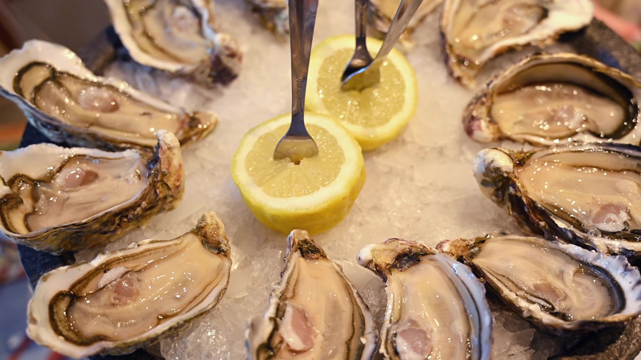 Fresh oysters displayed on crushed ice with sliced lemons in a seafood restaurant setting