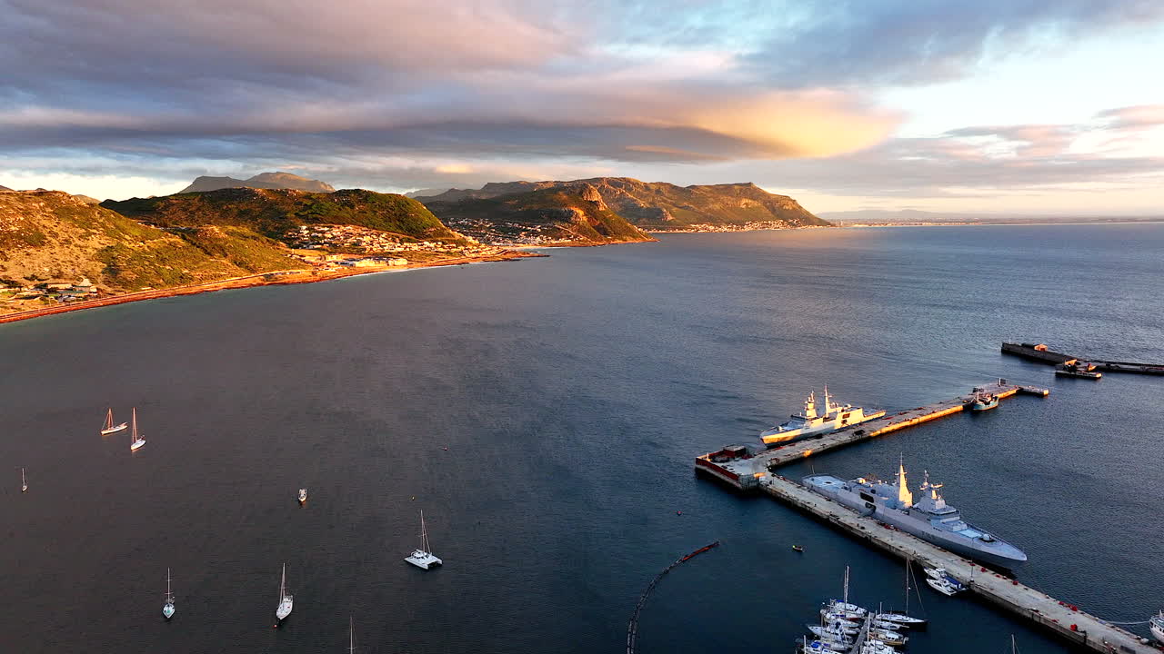 Aerial cinematic drone sunrise Simon's Town naval boat marina fishing small quite city Cape Town South Africa early sunlight clouds Table Mountain Fish Hook Muizenberg over bay backward movement